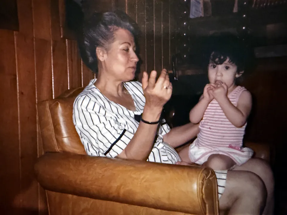 La abuela Guadalupe con Estefany de niña en un sillón de piel, en la casa familiar